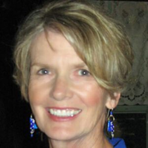 A woman with short blonde hair wearing blue earrings.