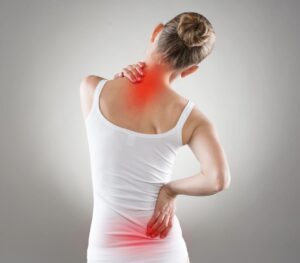 A woman in white shirt holding her back with red dot